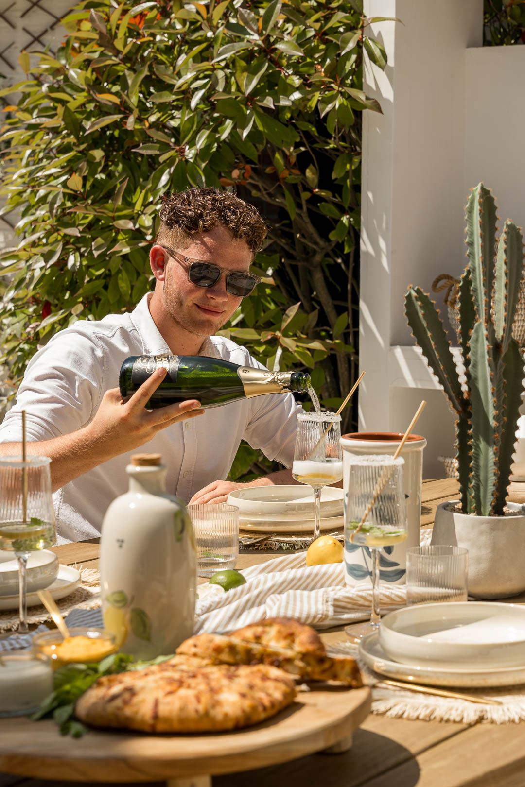 Menschen essen zusammen an einem Gartentisch im Ibiza Stil